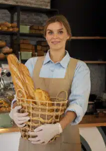 Woman baker holding a basket of artisan bread in a bakery