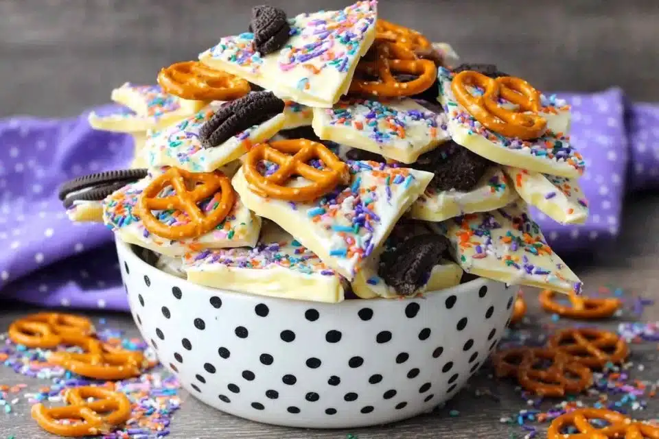 Colorful Halloween Candy Bark with sprinkles and chocolates on a white plate