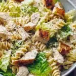 Bowl of Chicken Caesar Pasta Salad topped with parmesan and croutons.